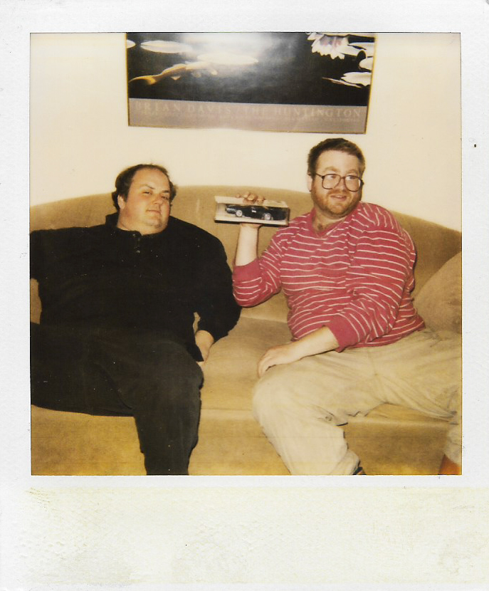 Rich and Brent sitting on a couch holding a toy car in the 1990s